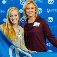 Two alumni pose for a photo with the GV flag